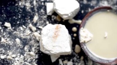 Multani mitti ya da Fuller 'in toprağının siyah bir yüzey üzerindeki yakın çekim görüntüsü ve yüz maskeleri ve doğal olarak parlayan cilt için yüz maskeleri olarak kullanılan çamur bir kaseye yapıştırılması. 24FPS 'te HD görüntüler.