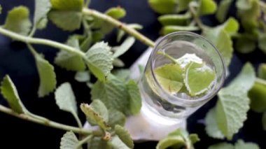 Dolly 'nin Trachyspermum ammi ya da Ajwain' in çekimleri bir bardakta ayrılan suyla birlikte siyah bir yüzeyde, HD görüntüsü 24FPS.