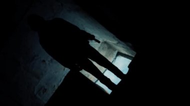 Kapüşonlu bir adamın dramatik ışıklarla ayakta durduğu film gibi bir korku filmi. HD görüntüler.