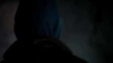 Kapüşonlu bir adamın dramatik ışıklarla ayakta durduğu film gibi bir korku filmi. HD görüntüler.