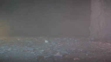 Düşen bir binanın enkazı ve tozu üzerinde yürüyen bir memurun ayaklarının sinematik görüntüsü..