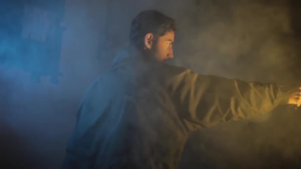 バックサイドは バックグラウンドでいくつかの煙を歩く銃で訓練されたプロのショット 劇的な照明 歩いている男のHd映像 ピストルを持つ兵士 — ストック動画