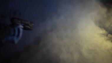 Arka planda biraz duman ve dramatik ışıklandırma olan silahlı bir memurun arka plan çekimi. Yürüyen bir adamın HD görüntüleri. Silahlı bir asker..