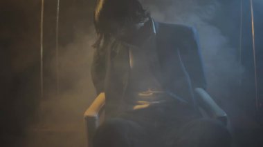 Sinema gibi, yaratıcı dramatik ışıklandırması ve duman elementi olan gizemli bir odada sandalyeye bağlanmış bir adamın görüntüsü. HD - 24 Fps - Fahişeler
