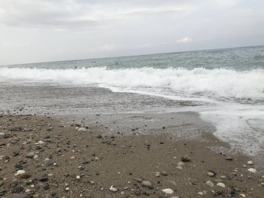 Deniz dalgaları ve arka planda kum olan güzel sahil.