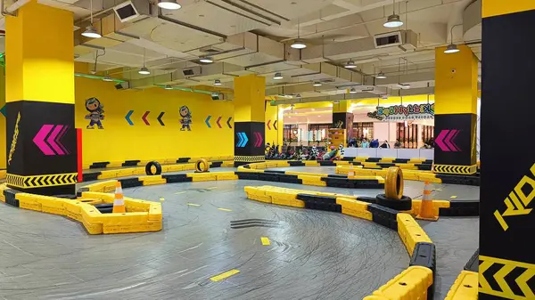 Balikpapan, Endonezya - 27 Temmuz 2024: Canlı sarı madalyaları, yarışçıları ve kareli bayrakları olan enerjik iç saha go-kart pisti. Eğlence ve aile eğlencesi için ideal..
