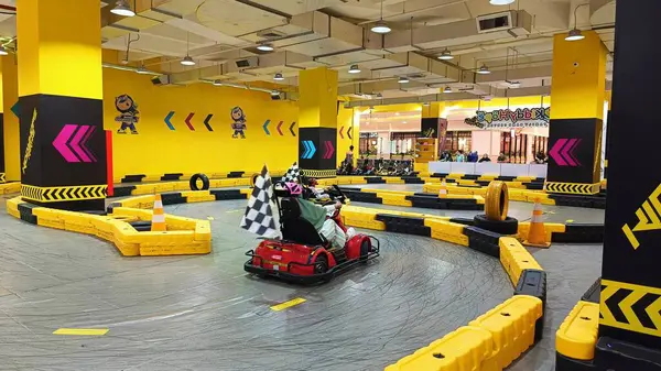 Balikpapan, Endonezya - 27 Temmuz 2024: Canlı sarı madalyaları, yarışçıları ve kareli bayrakları olan enerjik iç saha go-kart pisti. Eğlence ve aile eğlencesi için ideal..
