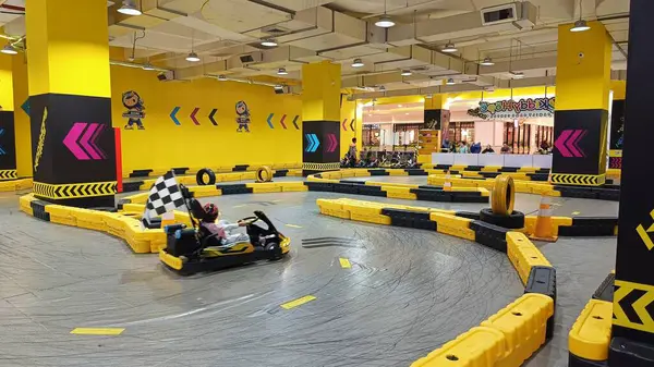 Balikpapan, Endonezya - 27 Temmuz 2024: Canlı sarı madalyaları, yarışçıları ve kareli bayrakları olan enerjik iç saha go-kart pisti. Eğlence ve aile eğlencesi için ideal..