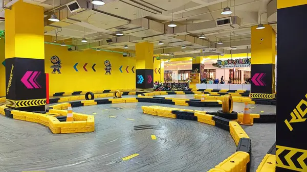 Balikpapan, Endonezya - 27 Temmuz 2024: Canlı sarı madalyaları, yarışçıları ve kareli bayrakları olan enerjik iç saha go-kart pisti. Eğlence ve aile eğlencesi için ideal..