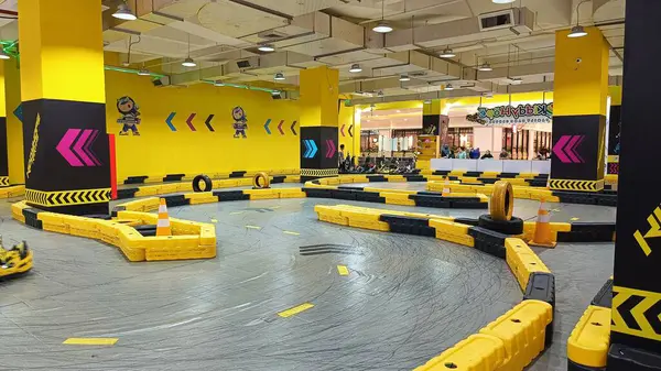 Balikpapan, Endonezya - 27 Temmuz 2024: Canlı sarı madalyaları, yarışçıları ve kareli bayrakları olan enerjik iç saha go-kart pisti. Eğlence ve aile eğlencesi için ideal..