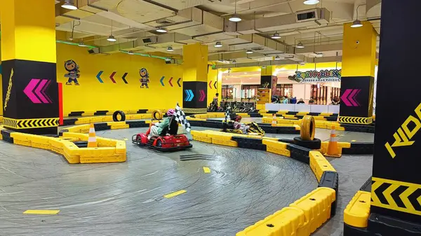 Balikpapan, Endonezya - 27 Temmuz 2024: Canlı sarı madalyaları, yarışçıları ve kareli bayrakları olan enerjik iç saha go-kart pisti. Eğlence ve aile eğlencesi için ideal..