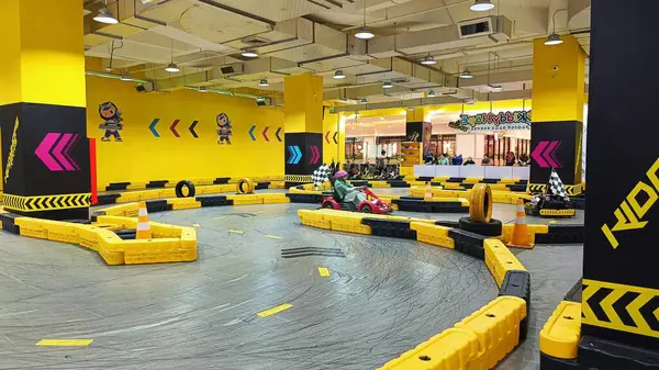 Balikpapan, Endonezya - 27 Temmuz 2024: Canlı sarı madalyaları, yarışçıları ve kareli bayrakları olan enerjik iç saha go-kart pisti. Eğlence ve aile eğlencesi için ideal..