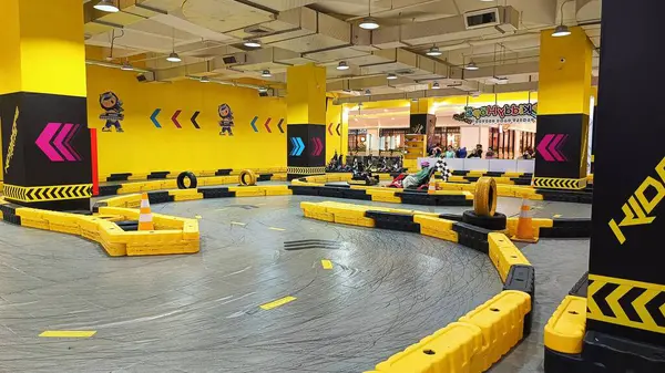 Balikpapan, Endonezya - 27 Temmuz 2024: Canlı sarı madalyaları, yarışçıları ve kareli bayrakları olan enerjik iç saha go-kart pisti. Eğlence ve aile eğlencesi için ideal..