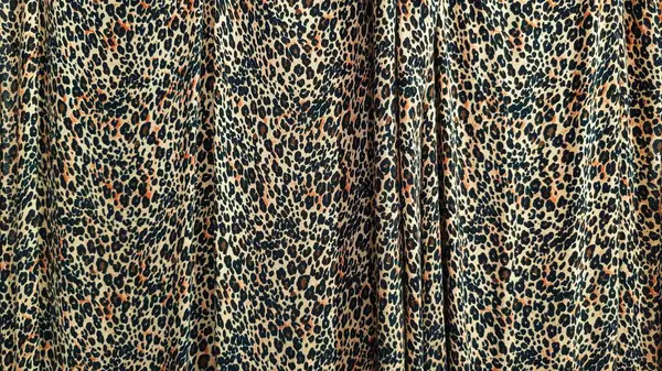 Leopar desenli kumaş perdelerin kapanışı canlı ve karmaşık desenler sergiliyor. Görüntü, hayvandan esinlenilmiş tasarımın dokusunu ve vahşi hissini ön plana çıkarıyor. Moda temalı arka plan için mükemmel.