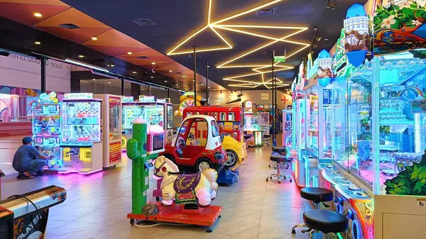 stock image Balikpapan, Indonesia - August 31, 2024: Vibrant arcade with neon lights, game machines, and plush toys. Captures the lively atmosphere of entertainment and fun in a modern indoor amusement setting.