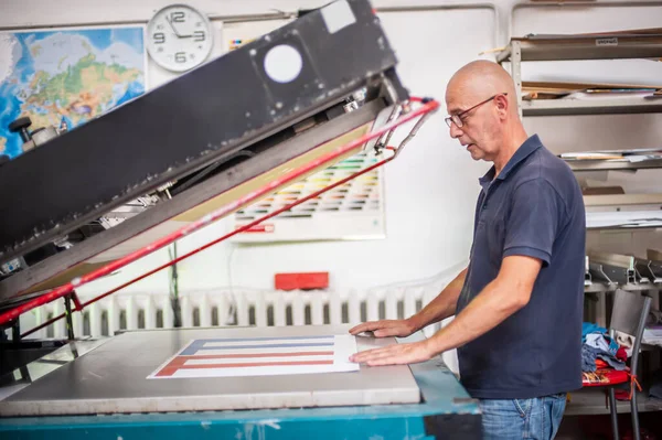 在印刷厂 一位经验丰富的技术员在一台丝网印刷机上工作 生产工作 检查印刷质量 — 图库照片
