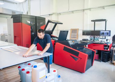 Matbaada modern büyük baskı makinesi olan profesyonel bir işçi. Yazdırma endüstrisi konsepti.