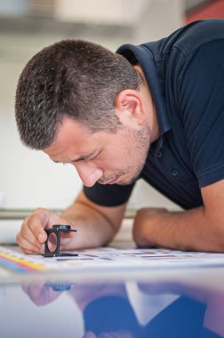 Kullanılmış renk terazileri, silindir ve yönetim renk düzeltmeleri basımı sürecindeki genç adam. Spektrofotometre, baskı ölçümü.