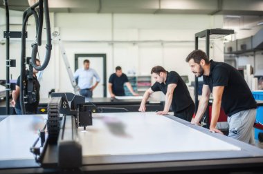 Profesyonel grafik teknisyenleri, bir matbaa ve matbaada çok çeşitli makinelerle çalışıyorlar.