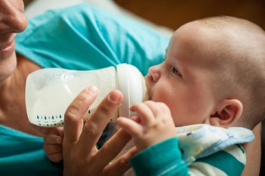 Annesinin yakın plan detaylı görüntüsü beslenme şişesinden küçük bebeğini besliyor.