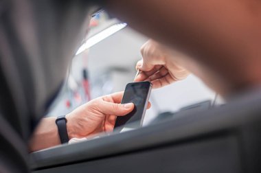 İş yeri üst görünümü, yakın plan. Bir elektronik tamir atölyesinde, tamirci akıllı telefonu tamir eder, cımbızı bir çok iş aletinden biri olarak kullanır.