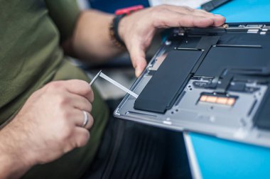 Technical support and fixing gadgets problems. Servicing, repairing, cleaning, maintaining computers. Repair shop. Hardware maintenance. Male technicians fixing disassembled laptop parts. 