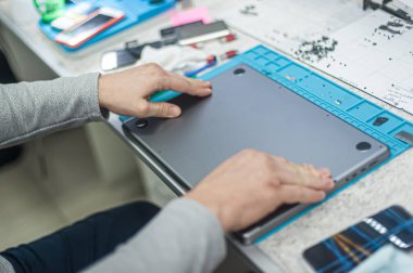 Close-up of specialized manual cleaning of laptop, screen, notebook, keyboard, case, from dust. Cleaning accessories: small vacuum cleaner, brush, cloth, spray.. Technical support and solving problems with gadgets. It is the service and maintenance o