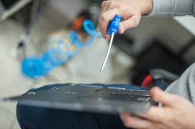 Close-up of specialized manual cleaning of laptop, screen, notebook, keyboard, case, from dust. Cleaning accessories: small vacuum cleaner, brush, cloth, spray.. Technical support and solving problems with gadgets. It is the service and maintenance o