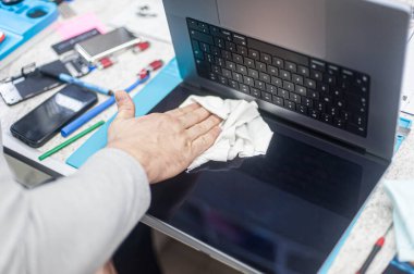 Close-up of specialized manual cleaning of laptop, screen, notebook, keyboard, case, from dust. Cleaning accessories: small vacuum cleaner, brush, cloth, spray.. Technical support and solving problems with gadgets. It is the service and maintenance o