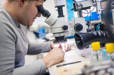 The employees in the workshop do their daily work. A workbench full of various tools and items needed to repair electrical appliances