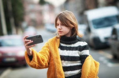 Sarı kürklü, sosyal medya etkileyicisi, siyah köpeğiyle şehirde gezen, akıllı telefon kullanan genç ve güzel bir kadın..