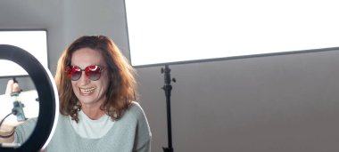 Güzel görünümlü bir kadın blogcunun portresi, yaşam tarzı internet etkileyicisi. Gülümseyen vlogger kadını cep telefonuna bakıyor, video çağrısı yapıyor, video çekiyor.