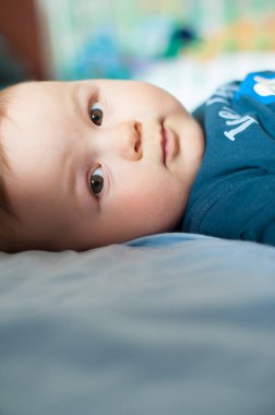 Yatakta yatıp kameraya bakan sevimli erkek bebek portresi. Mesaj için yer. Aşk ve aile duyguları