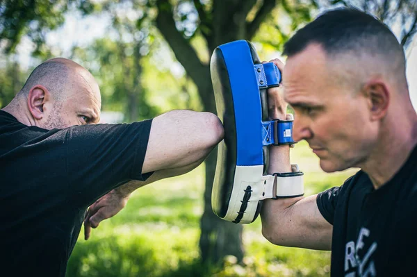 ムエタイのトレーナーはフォーカスミットを保持しています エルボーキック技術の訓練とパッドでのデモンストレーション 武道の練習 — ストック写真