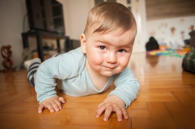 Sevimli erkek bebek yerde sürünüyor, dünyayı keşfediyor ve hareket etmeyi öğreniyor. Ön manzara. Aşk ve aile duyguları