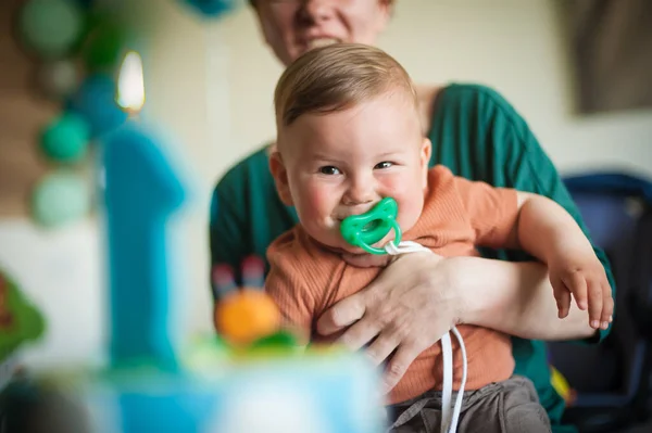 stock image Cute baby boy celebrates his first birthday with his family at home. Cake and candle in the shape of number one