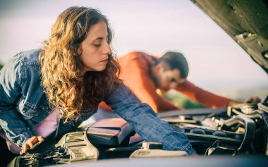 Genç bir çift yolda araba arızası yaşadı. Çok üzgün duruyorlar, kaputu açıp bozuk motoru tamir etmeye çalışıyorlar.