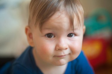 Küçük oğlan evin zemininde sürünüyor ve kameraya bakıyor. Ön manzara. Çocukların masumiyeti. Aşk ve aile duyguları