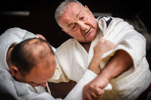 Close-up portrait of judo sensei master instructor in traditional gi kimono demonstrate judo technique
