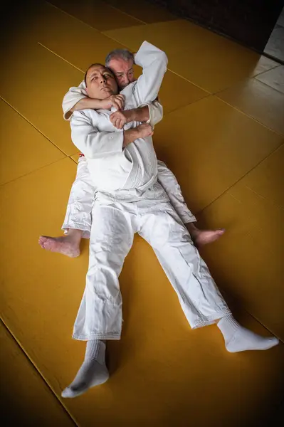 Judo sensei master instructor in traditional gi kimono demonstrate judo ground technique on tatami