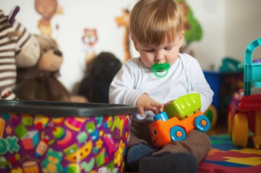 Sevimli erkek bebek renkli oyuncaklarıyla oturma odasında oynuyor. Eğitim oyuncakları, çocuk gelişimi