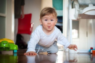 Güzel gülümseyen bebek evin içinde emekliyor ve çocuk odasında oyuncaklar oynuyor. Neşe ve mutluluk kavramı. Aşk ve aile duyguları
