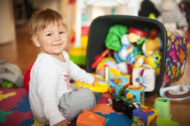 Sevimli erkek bebek renkli oyuncaklarıyla oturma odasında oynuyor. Eğitim oyuncakları, çocuk gelişimi