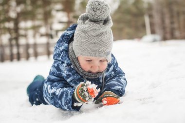 Güzel bir kış günü dışarıda karda oynayan sevimli, gülen çocuk. Doğayı keşfeden çocuk. Küçük çocuklar için kış aktiviteleri