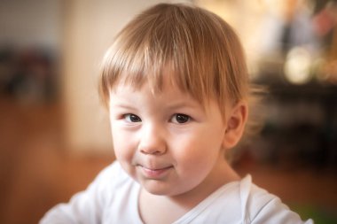 Kanepeye yaslanıp kameraya bakan mutlu, gülümseyen bir çocuğun portresi. Neşe ve mutluluk kavramı. Aşk ve aile duyguları