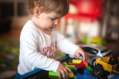 Lego blokları. Mutlu çocuk, şirin çocuk renkli plastik tuğlalarla oynuyor ve inşa ediyor.