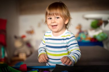 Sevimli erkek bebek renkli oyuncaklarıyla oturma odasında oynuyor. Eğitim oyuncakları, çocuk gelişimi