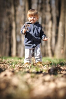 Bebekler sonbahar macerası. Meraklı çocuk yere düşen yaprakların arasına çömelmiş, doğanın mucizelerini keşfediyor. Çocuk dışarıda oynuyor.