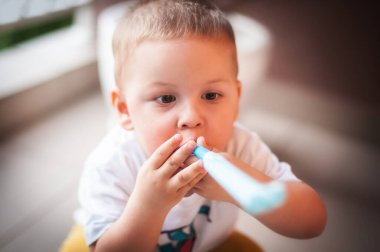 Küçük mutlu çocuk arkadaşlarıyla iki yıllık doğum gününü kutluyor, folyo parti kornasını çalıyor, mavi ve beyaz parti düdüğünü çalıyor. Eğlence, neşe, kutlama ve tatil
