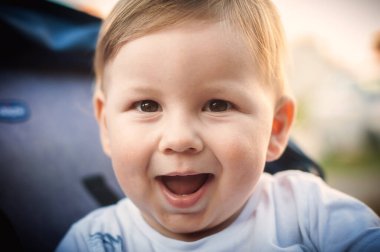 Neşeli bir erkek bebek, güneşli bir öğleden sonranın tadını çıkarırken bulaşıcı bir gülümseme sergiliyor..